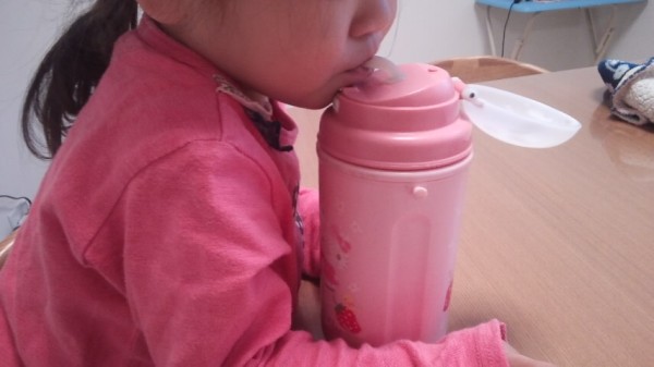ストロータイプの水筒から飲み物を飲む２歳児